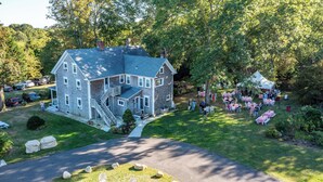 A large two-story house with a covered porch and a small staircase. - Coastal Farmhouse at Ninigret Pond - 3.1 Mi to beach - Sleeps 4-12 people (Charlestown)