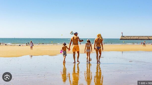 A beach scene with a family walking along the shore. - Loving cocoon with furnished balcony (Les Sables-d'Olonne)