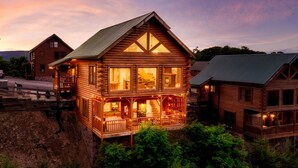 A large log cabin with multiple levels, a balcony, and a porch area.