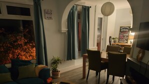 A cozy living room with a sofa, coffee table, and a dining area with chairs and a table. - Private Entire House - 3 Bedrooms, Garden, Parking (Brighton)