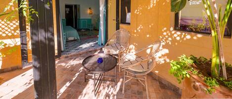An outdoor patio with wicker chairs, a round table, and potted plants.