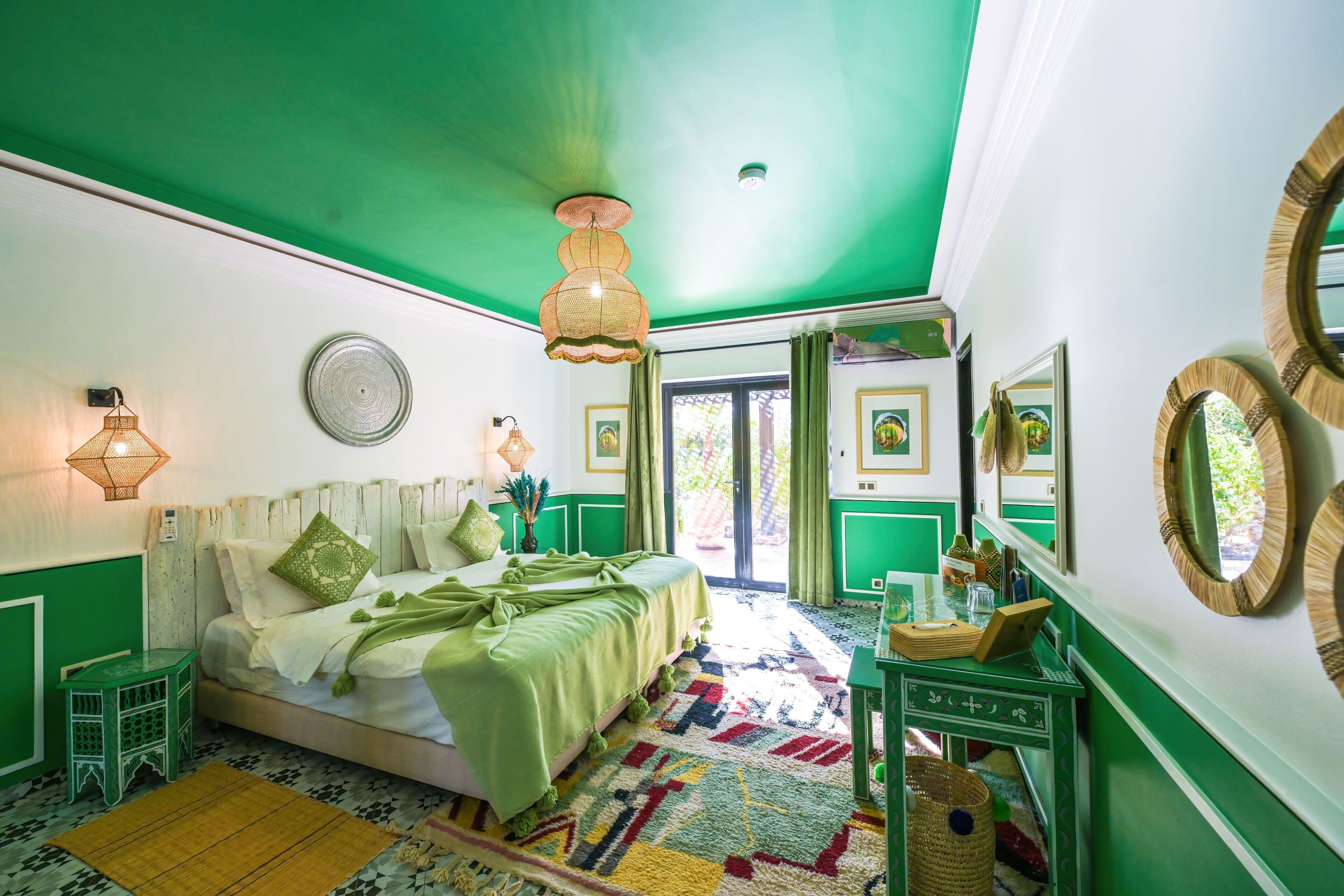 Una stanza con un letto, un muro verde, un tappeto decorato e un pavimento verde.