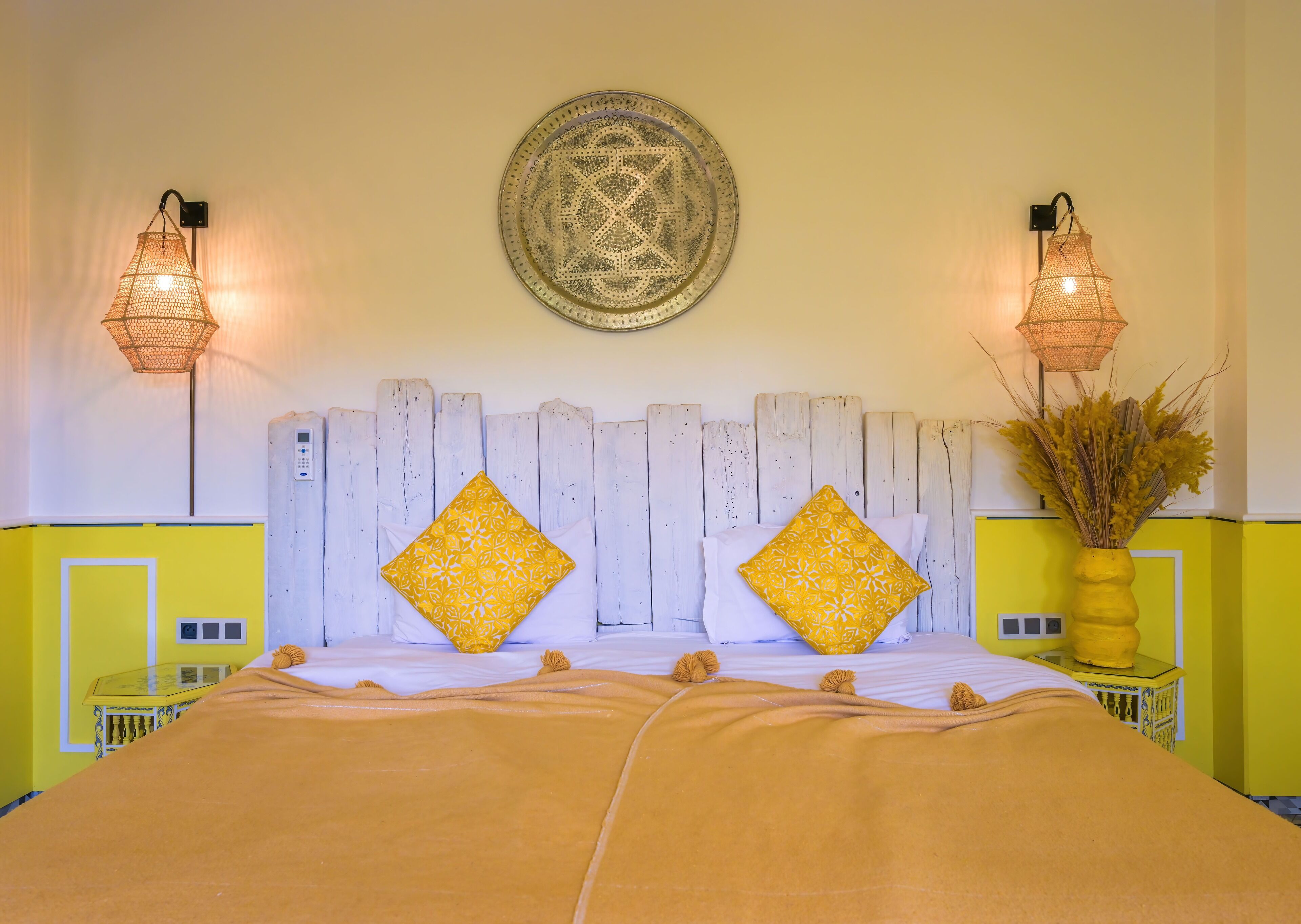 A bed with two pillows, a headboard, and two wall-mounted lamps.