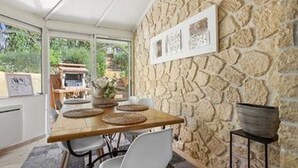 Un comedor con pared de piedra, mesa de madera y sillas.