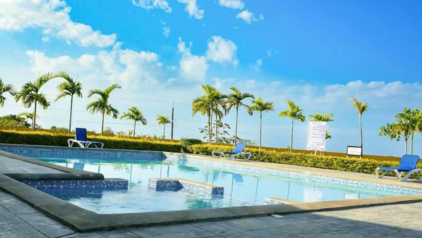 A swimming pool with lounge chairs and palm trees. - Captivating 2-bed House in Falmouth (Falmouth)