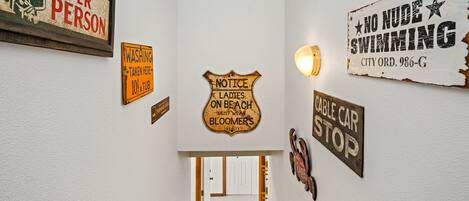 A hallway with various signs including 'Notice Ladies On Beach Must Wear Bloomers' and 'No Nude Swimming'.