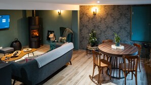 Ein modernes Wohnzimmer mit Sofa, Couchtisch, Kamin, Esstisch mit Stühlen und einer kleinen Weihnachtstanne.