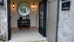 A modern entrance with a circular window, a bench, and a door. - Les Girauderies Chambres d'Hotes  (Floirac)