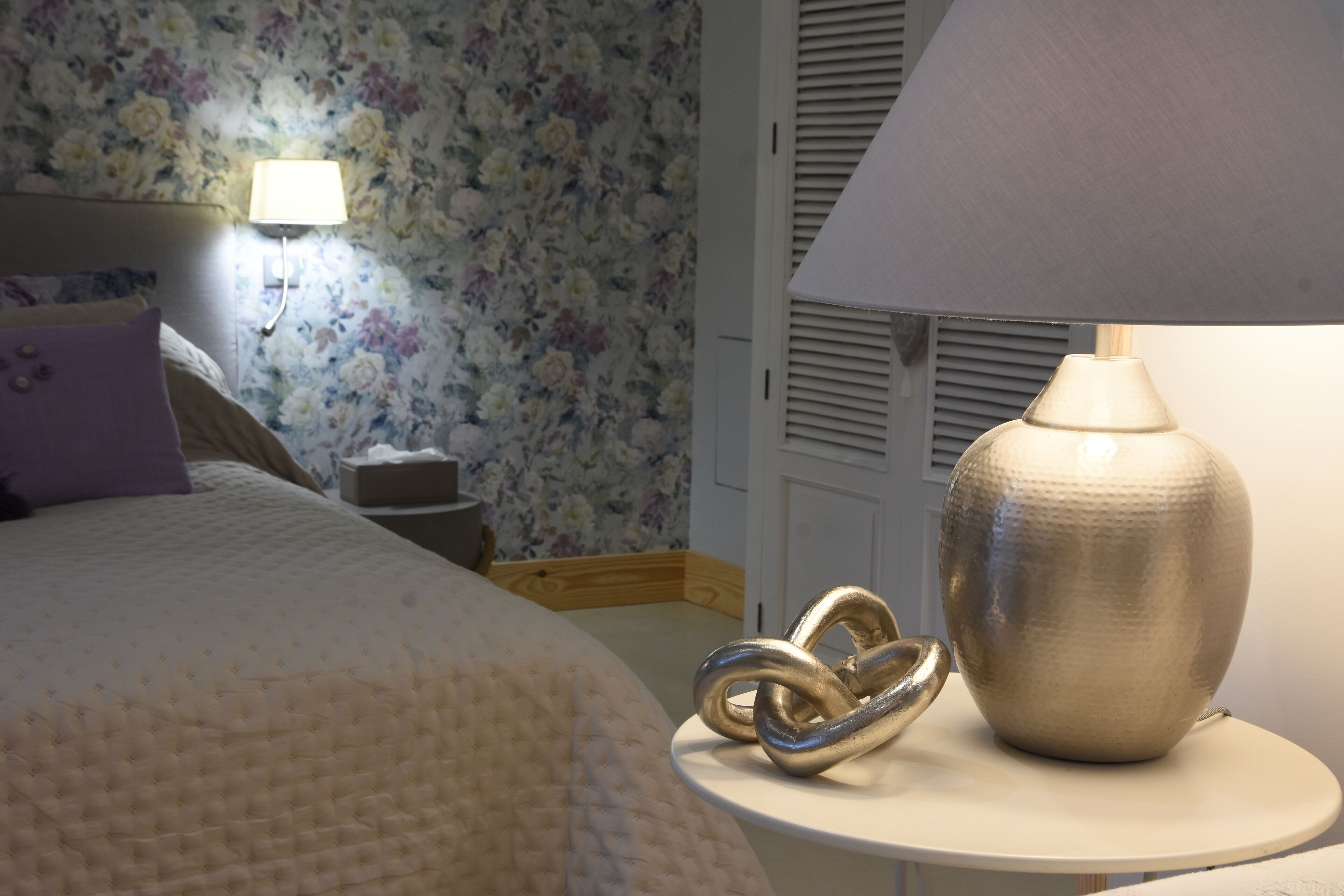 A bedroom with a bed, a nightstand, a lamp, and a decorative item on the nightstand.