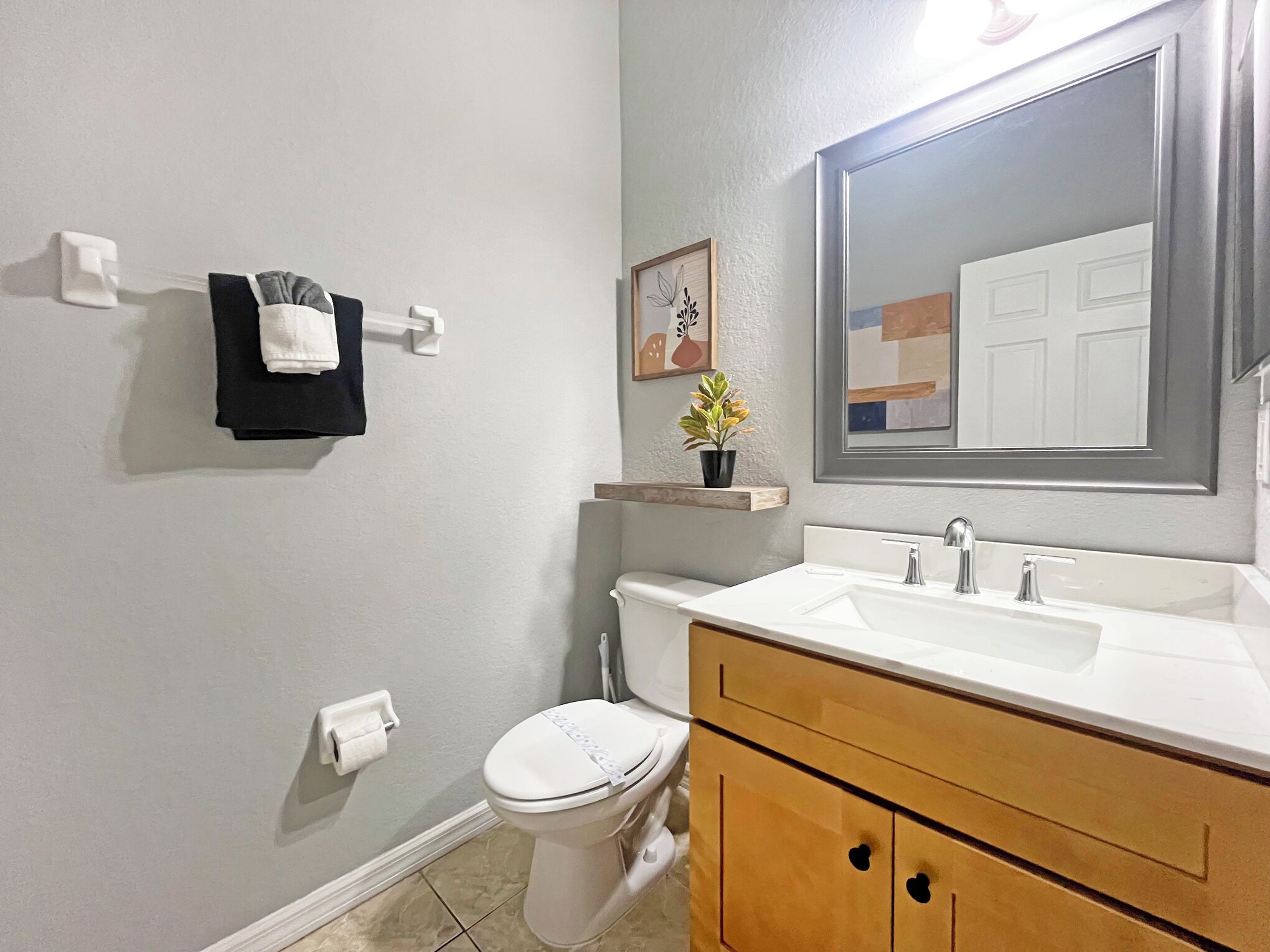 A bathroom with a toilet, sink, vanity, towel rack, and a mirror.