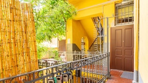 Un bâtiment jaune avec un escalier en métal et une porte marron.