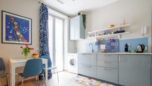 Une cuisine moderne équipée d’un lave-linge, un coin repas avec des chaises et un tapis coloré.
