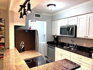 A modern kitchen with a black refrigerator, stainless steel microwave, and granite countertops. - I40 - Apt|Patio|11mi to Convention Ctr|Sleeps 2 (Irving)