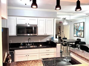 A modern kitchen with white cabinets, a built-in microwave, a stainless steel sink, and a granite countertop. - I40 - Apt|Patio|11mi to Convention Ctr|Sleeps 2 (Irving)