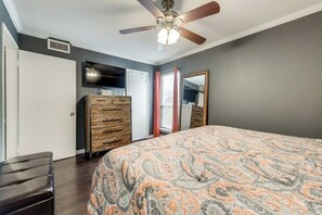 A bedroom with a bed, dresser, ceiling fan, and a television. - I40 - Apt|Patio|11mi to Convention Ctr|Sleeps 2 (Irving)