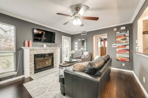 Una sala de estar con chimenea, un sofá, un ventilador de techo y un televisor.