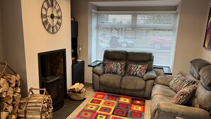 A living room with a fireplace, a sofa, a colorful rug, and a clock on the wall. - Modern house with a Tub!!! (Bangor)