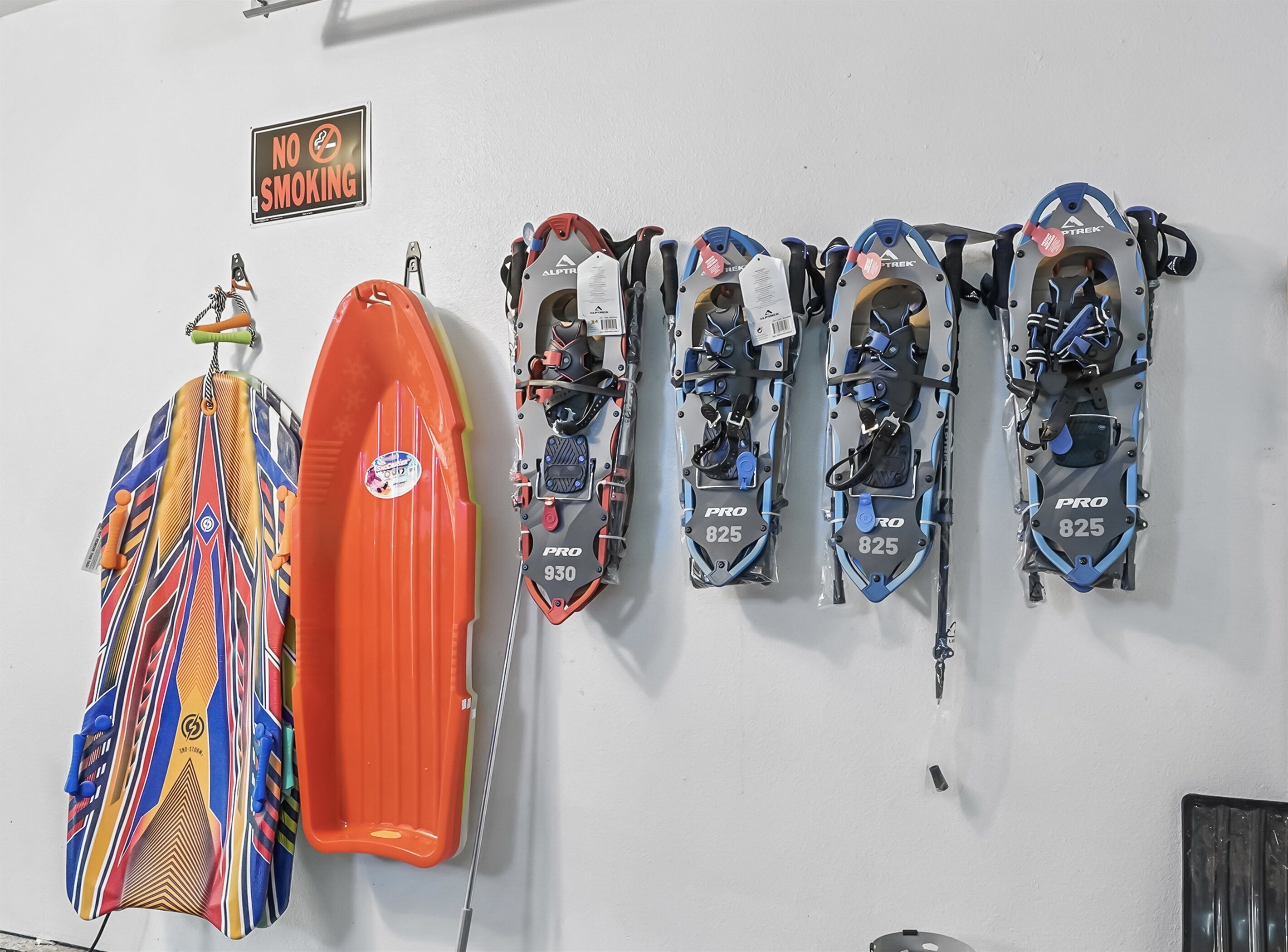 A wall with a 'No Smoking' sign and various snowboards and skis hanging on hooks.