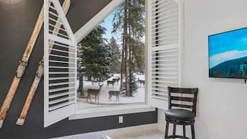A room with a large window, a chair, and a painting on the wall.