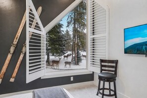 A room with a large window, a chair, and a painting on the wall.
