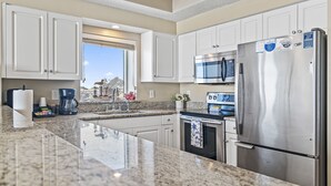 A modern kitchen with white cabinets, a stainless steel refrigerator, a microwave, and a coffee maker. - Majestic Sun B314*GulfViews*Owner's Garage*Hot Tub*Heated Pools*Beach Gears*Gym (Miramar Beach)