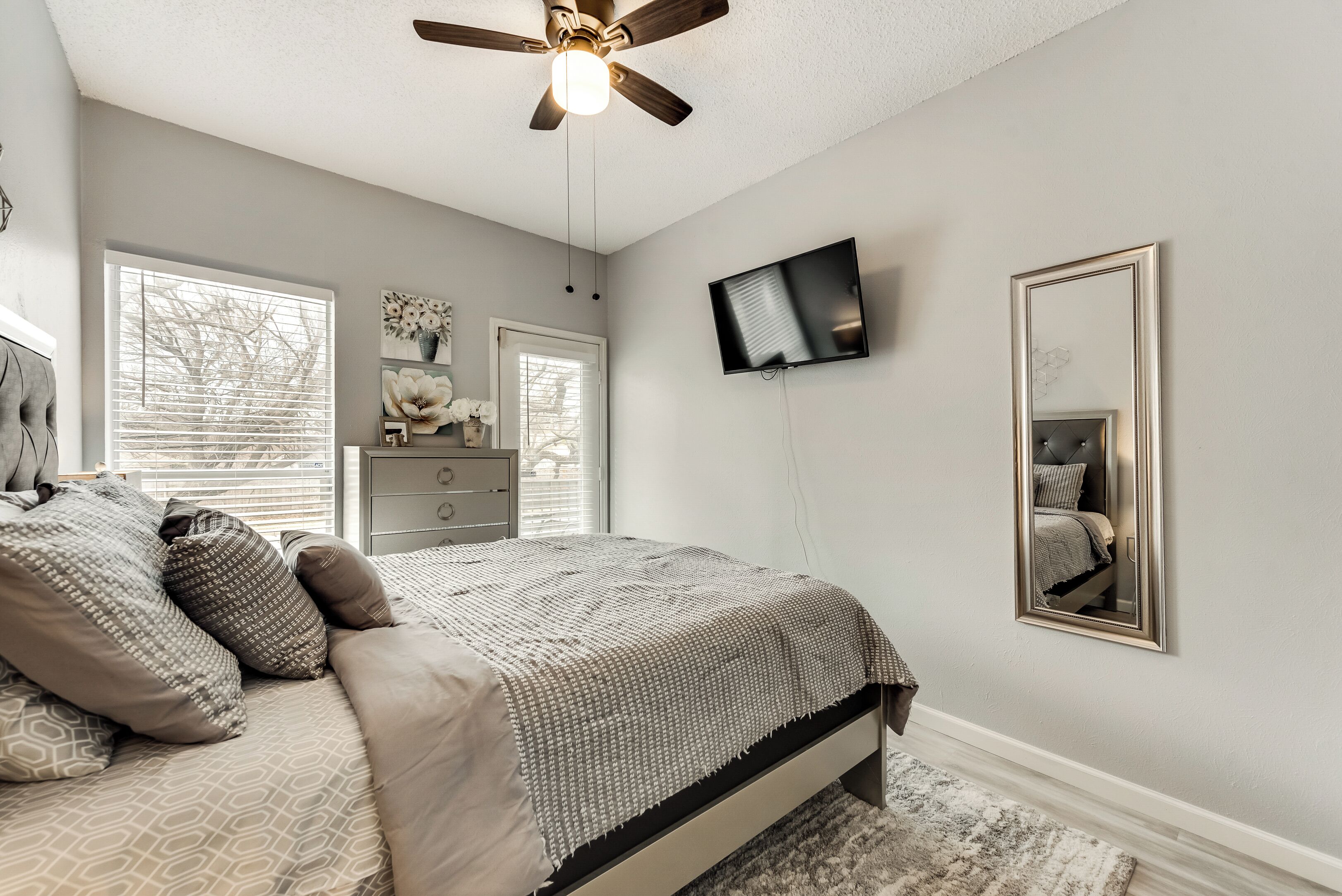 Une chambre à coucher avec un lit, une commode, un téléviseur et un ventilateur de plafond.