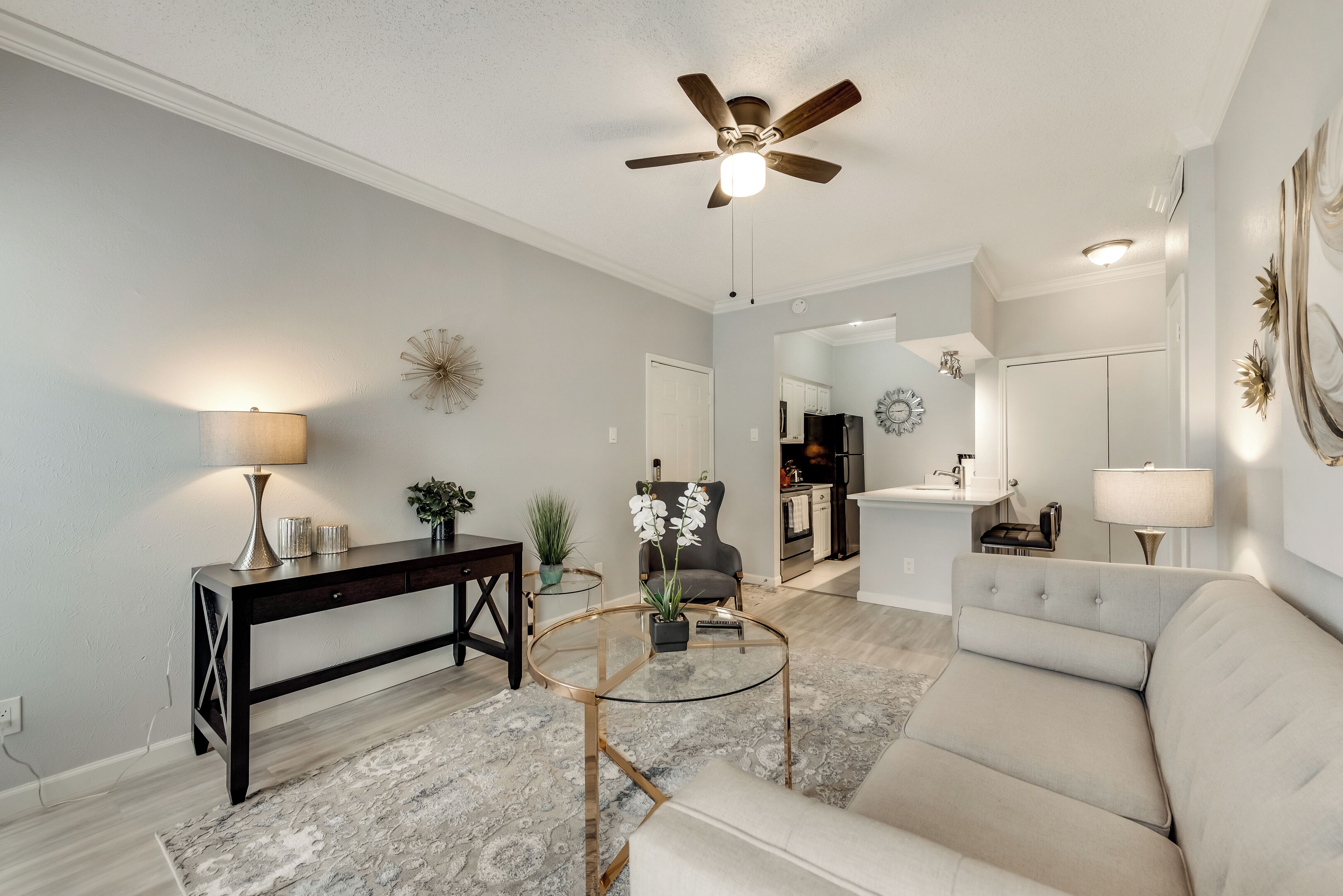 A living room with a ceiling fan, a sofa, a coffee table, and a side table with a lamp.