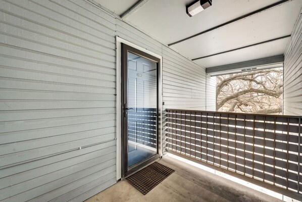 A covered porch with a sliding glass door, a metal gate, and a concrete floor.