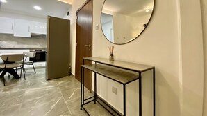 Cocina moderna con armarios blancos, piso de mármol y comedor con sillas.