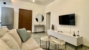 Una sala moderna con sofá, mesa de centro, televisor y chimenea.