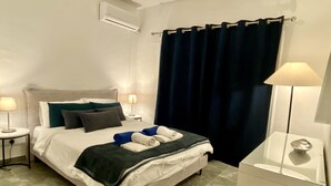 Una cama bien hecha con almohadas, una lámpara de noche y una mesita de noche.