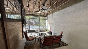Une pièce avec un plafond en bois, une porte vitrée donnant sur l’extérieur, une table avec des chaises et une vue sur le paysage.