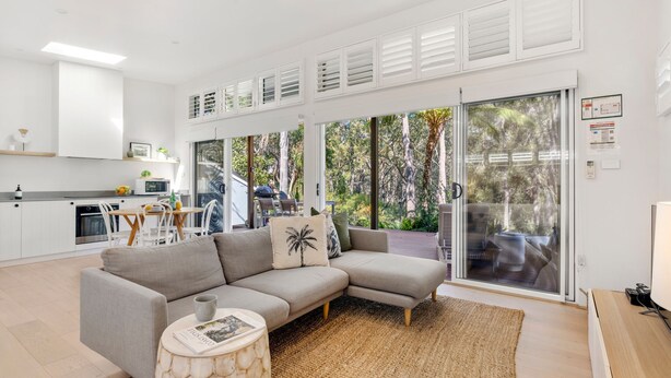 A modern living room with a grey sectional sofa, a small round coffee table, and a large sliding glass door leading to an outdoor area.