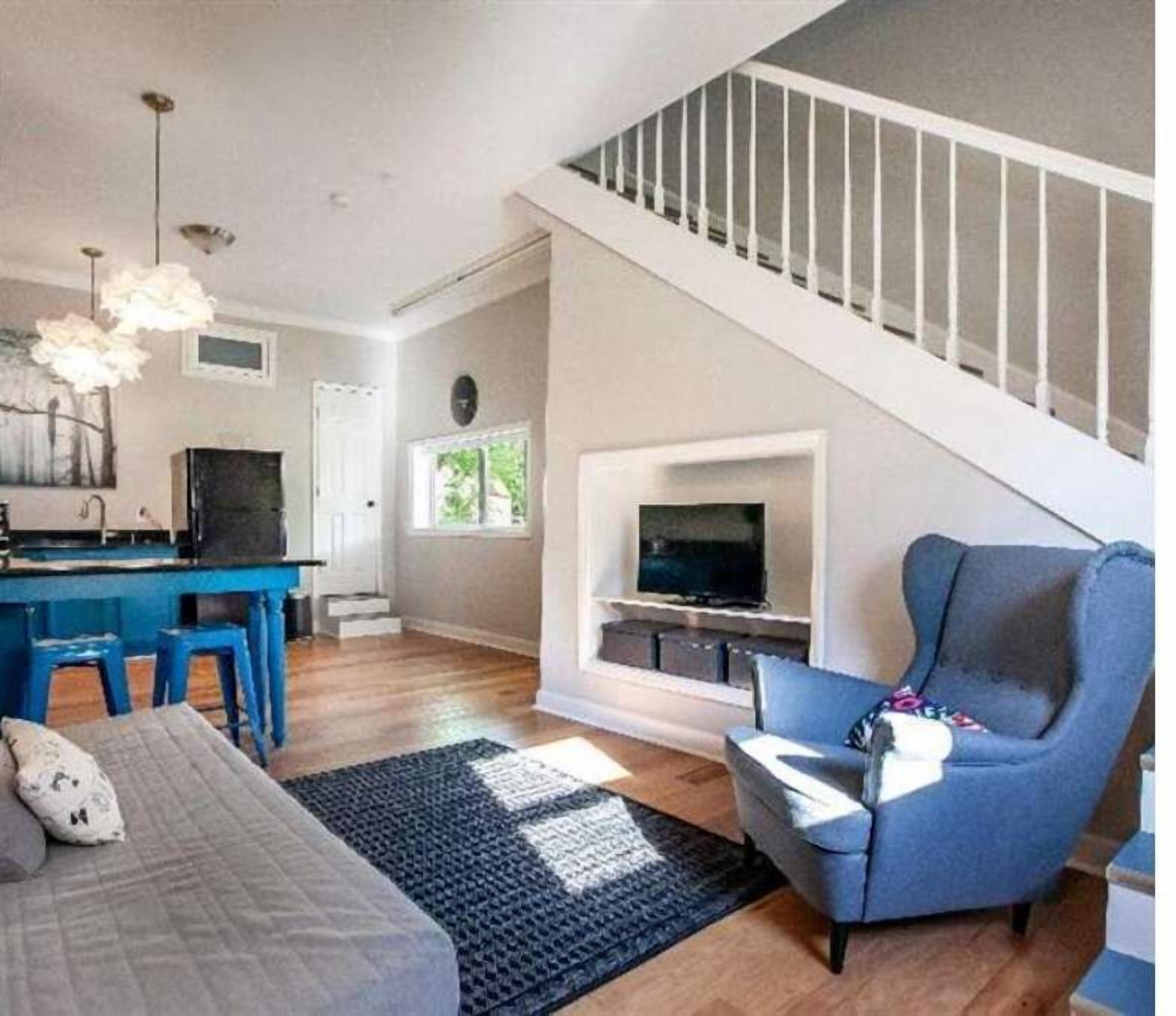 Un salon moderne avec un escalier, un coin repas et une cuisine.