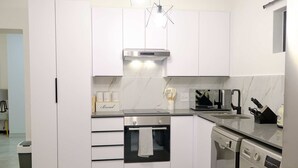 A modern kitchen with white cabinetry, a built-in oven, a dishwasher, and a coffee maker. - Medon Luxury Suites with power back up (Sandton)