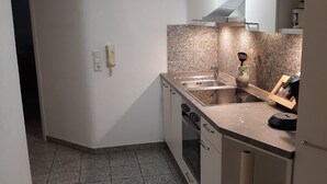 A compact kitchen with a granite countertop, a built-in oven, and a sink.