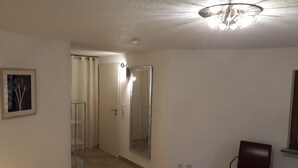 A bedroom with a bed, a chair, a mirror, and a door leading to another room.
