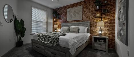 Un dormitorio con pared de ladrillo, cama con cabecera de madera, mesita de noche con lámpara, ventilador de techo y una ventana grande con persianas.