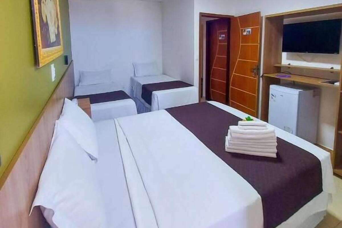 Une chambre d’hôtel avec deux lits, une télévision et un petit réfrigérateur.