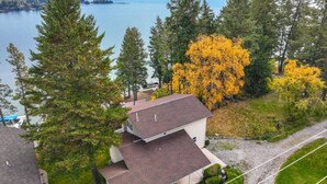 A two-story house with a sloped roof, surrounded by trees and a lake. - Somers Lookout on Flathead Lake, private dock (Somers)
