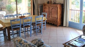 Un comedor con una mesa, sillas, un armario de madera y un sofá.