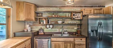 A modern kitchen with wooden cabinets, a stainless steel refrigerator, and a built-in sink.