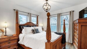 A four-poster bed with a wooden headboard, a nightstand with a lamp, and a dresser with drawers. - Riverside Renaissance - Spa!  King Beds! Beautiful Renaissance decor (Wichita)