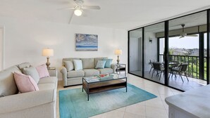 Una sala moderna con sofá, mesa de centro y un balcón con mobiliario de exterior.