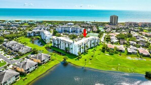 Un resort con varias edificaciones, una fuente central y vista al océano.