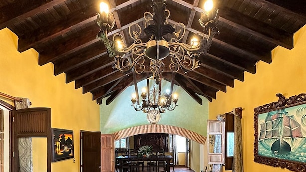 A spacious living area with a high wooden ceiling, a large chandelier, and a dining area in the background. - Sabor&arte (Antigua Guatemala)
