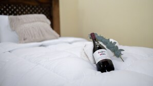 A bottle of Casillero del Diablo wine on a bed with white bedding and a wooden headboard. - Sabor&arte (Antigua Guatemala)