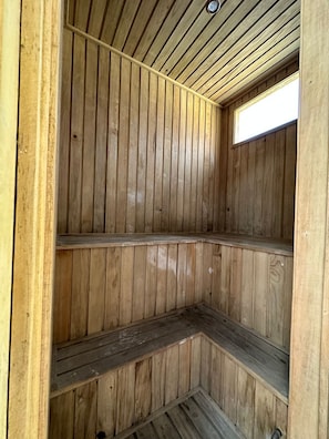 A wooden interior with a sloped ceiling and a small window.