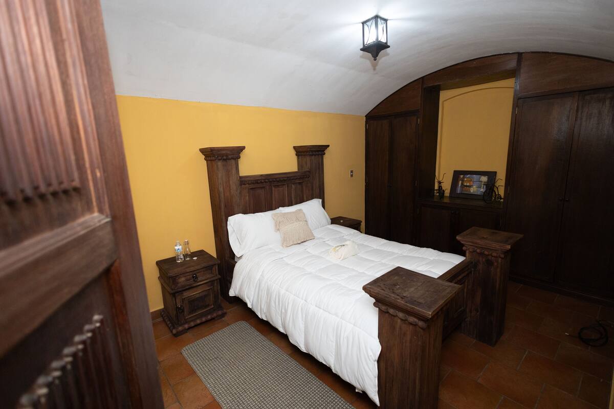 Une chambre à coucher avec un lit en bois, une table de chevet, une commode et un miroir.