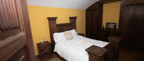 A bedroom with a wooden bed, a nightstand, a dresser, and a mirror.